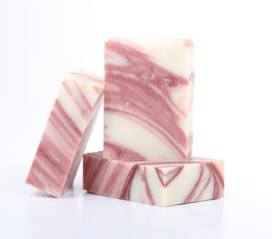 Three rectangular bars of soap with a pink and cream marble pattern, arranged on a clean white background. Peppermint soap, cold pressed and organic. Fair trade. 