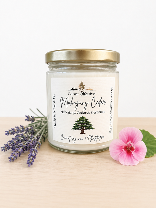 Mahogany teakwood candle, Candle jar with a label featuring a tree design, surrounded by lavender and a pink flower on a light background.