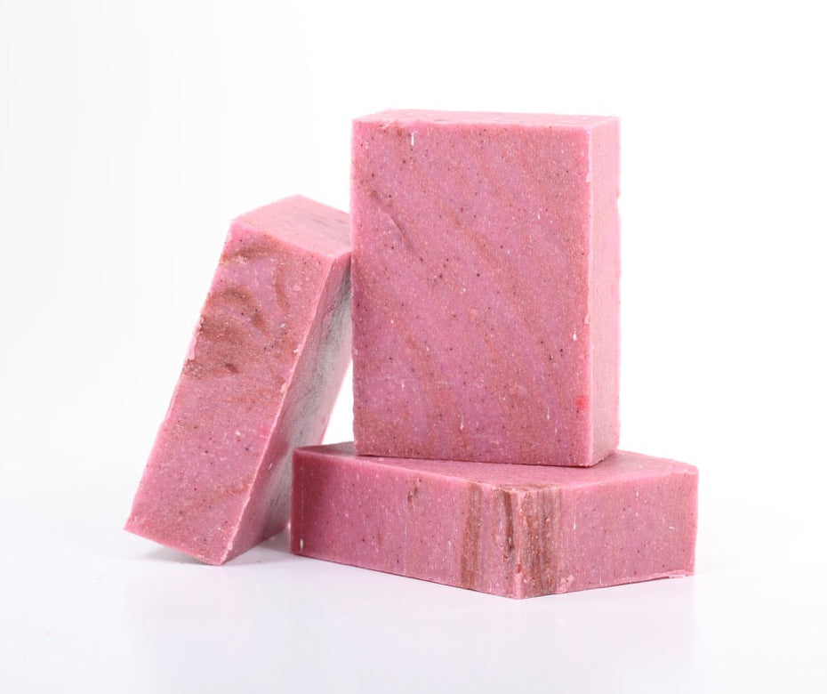 Three rectangular pink soap bars with natural marbled texture, arranged on a white 
background. Cold pressed and cranberry scented. 